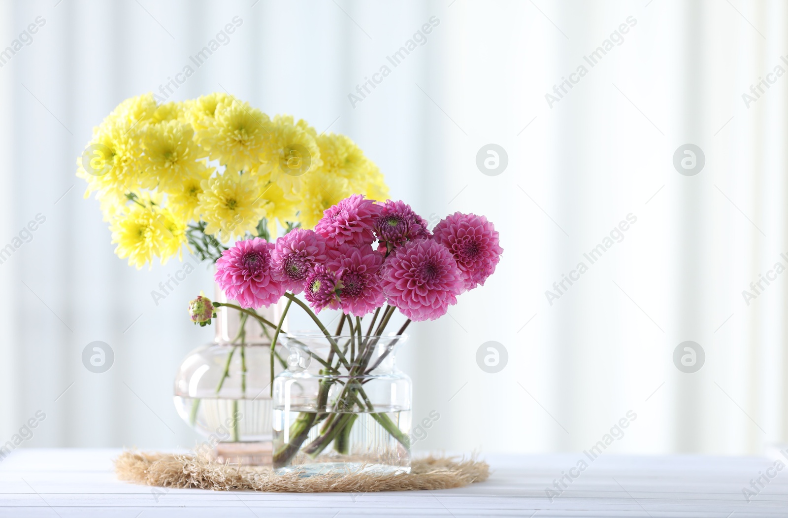 Beautiful flowers in vases on white wooden table at home. Space for text Photo of Beautiful flowers in vases on white wooden table at home. Space for text