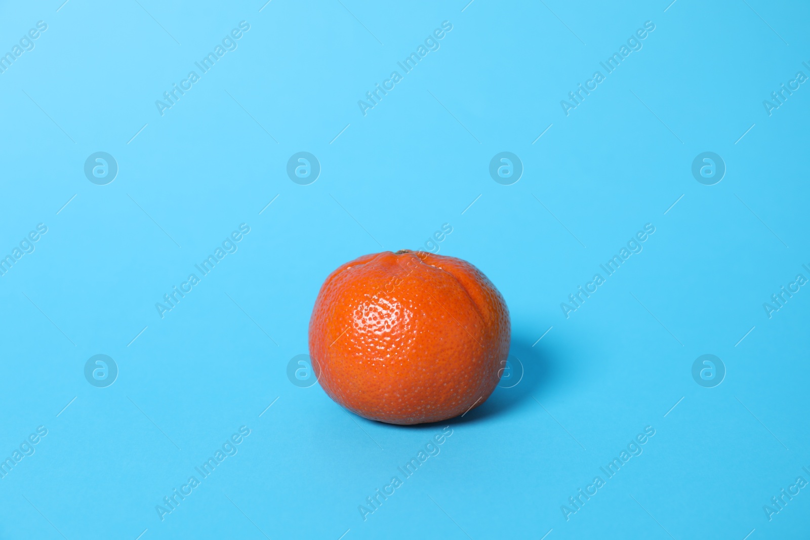 Photo of Fresh ripe tangerine on light blue background