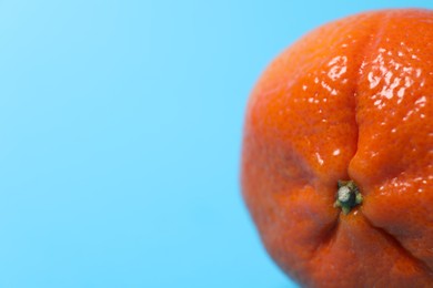 Photo of Fresh ripe tangerine on light blue background, closeup. Space for text