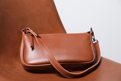 Photo of Stylish brown leather bag on chair, closeup