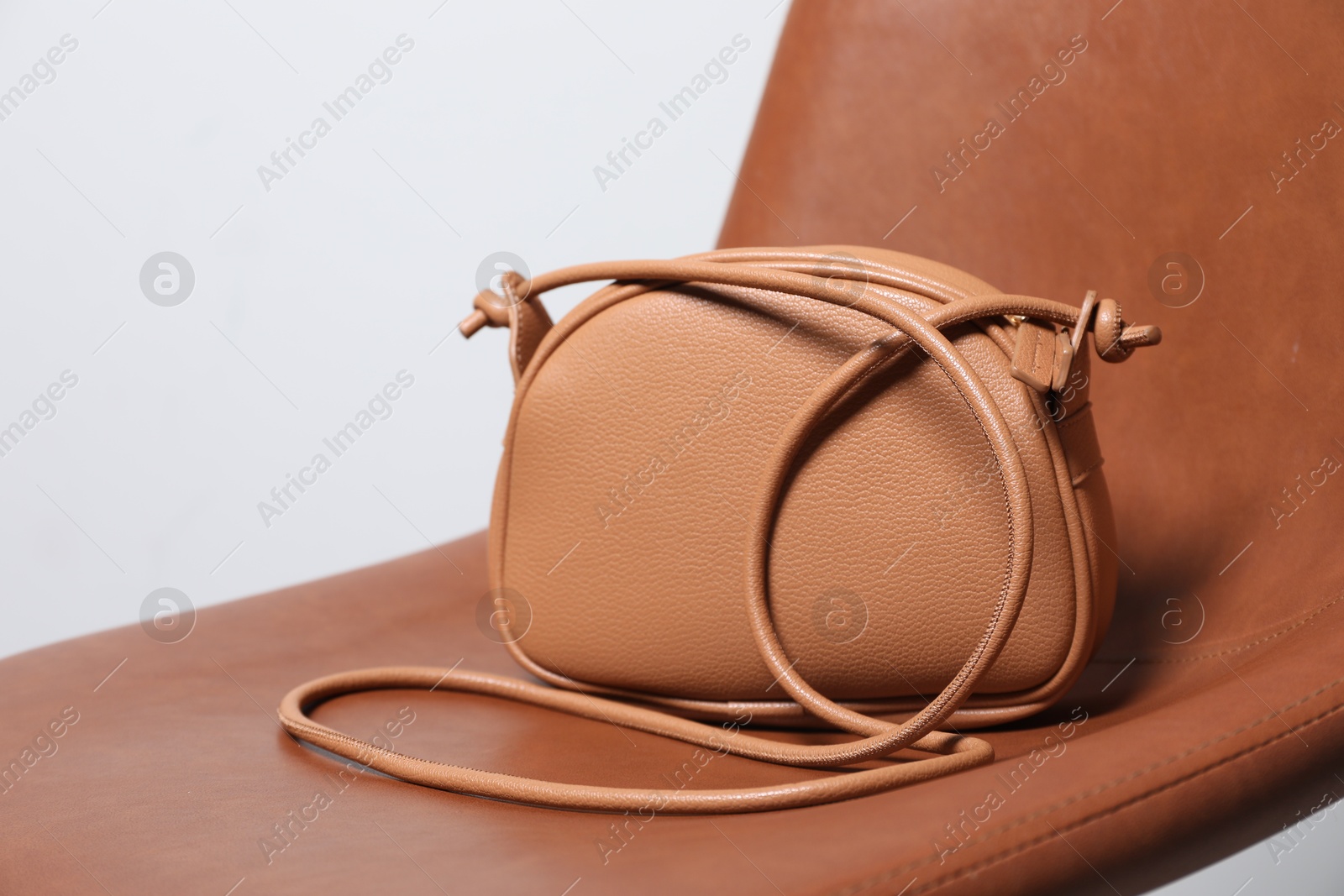 Photo of Stylish dark beige leather bag on brown chair, closeup