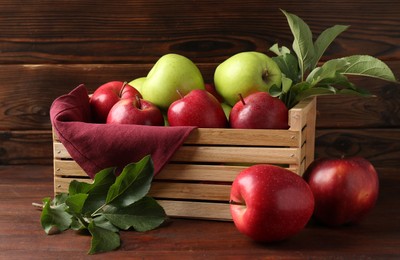 Photo of Ripe red and green apples in crate on wooden table