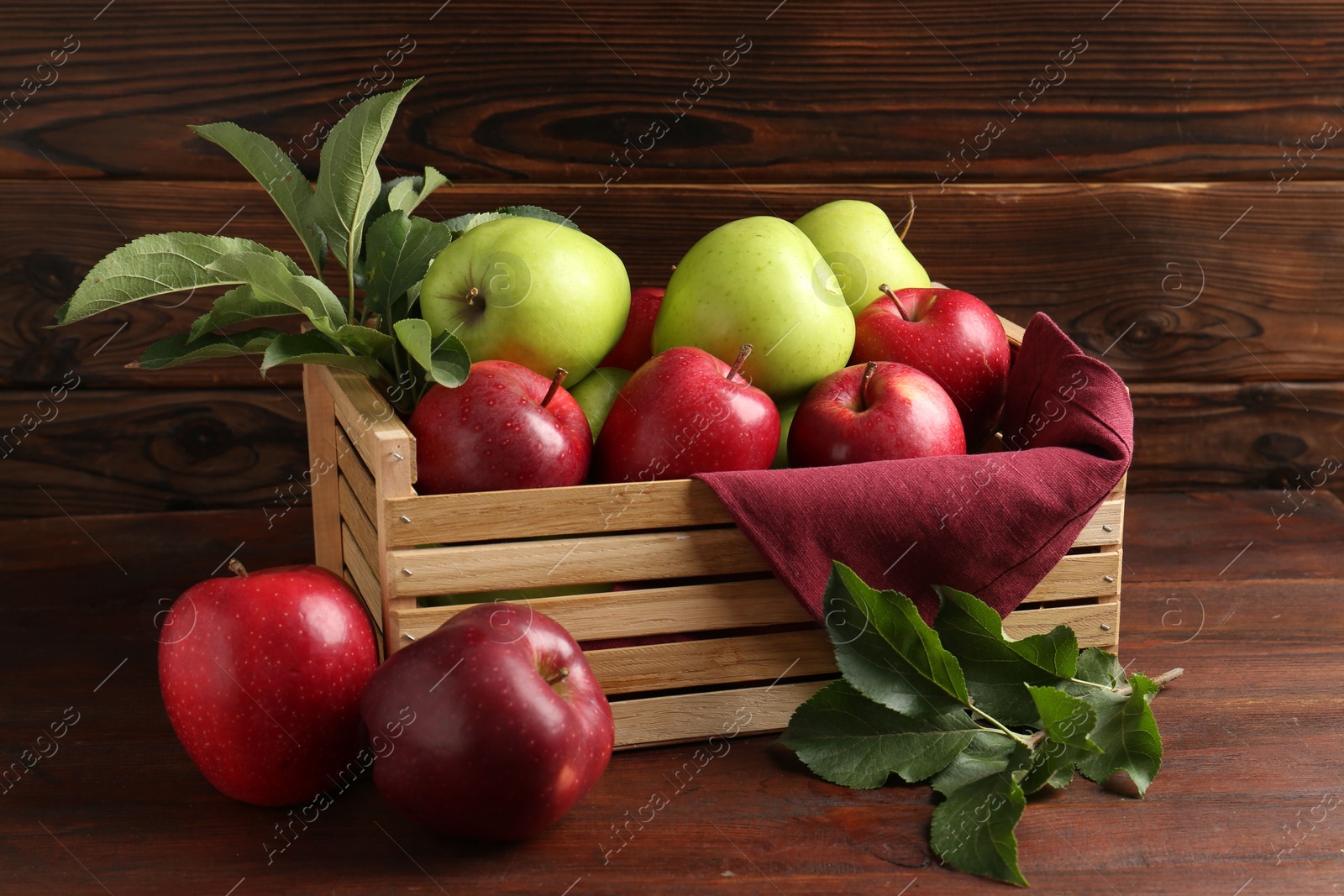 Photo of Ripe red and green apples in crate on wooden table