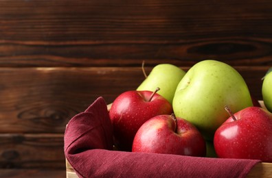 Photo of Ripe red and green apples in crate against wooden background, closeup