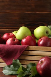 Photo of Ripe red and green apples in crate on table, closeup