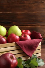 Photo of Ripe red and green apples in crate on table, closeup