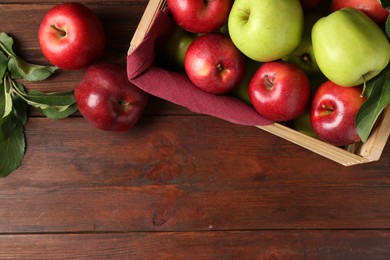 Photo of Ripe red and green apples in crate on wooden table, top view. Space for text