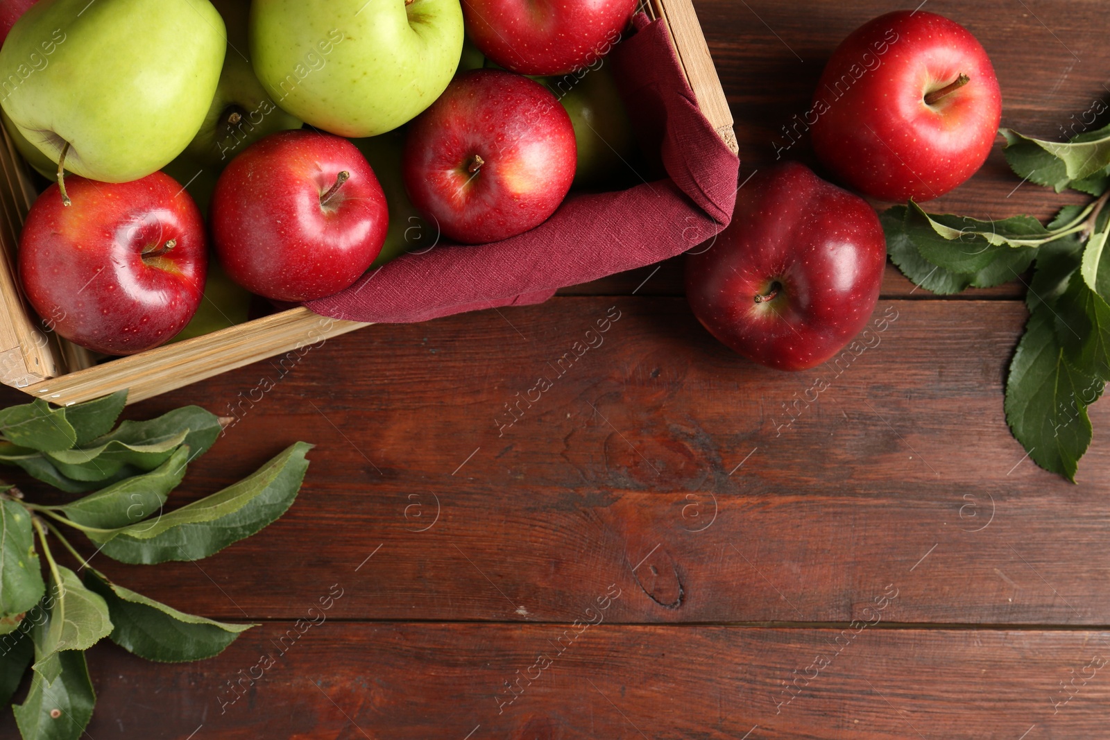 Photo of Ripe red and green apples in crate on wooden table, top view. Space for text