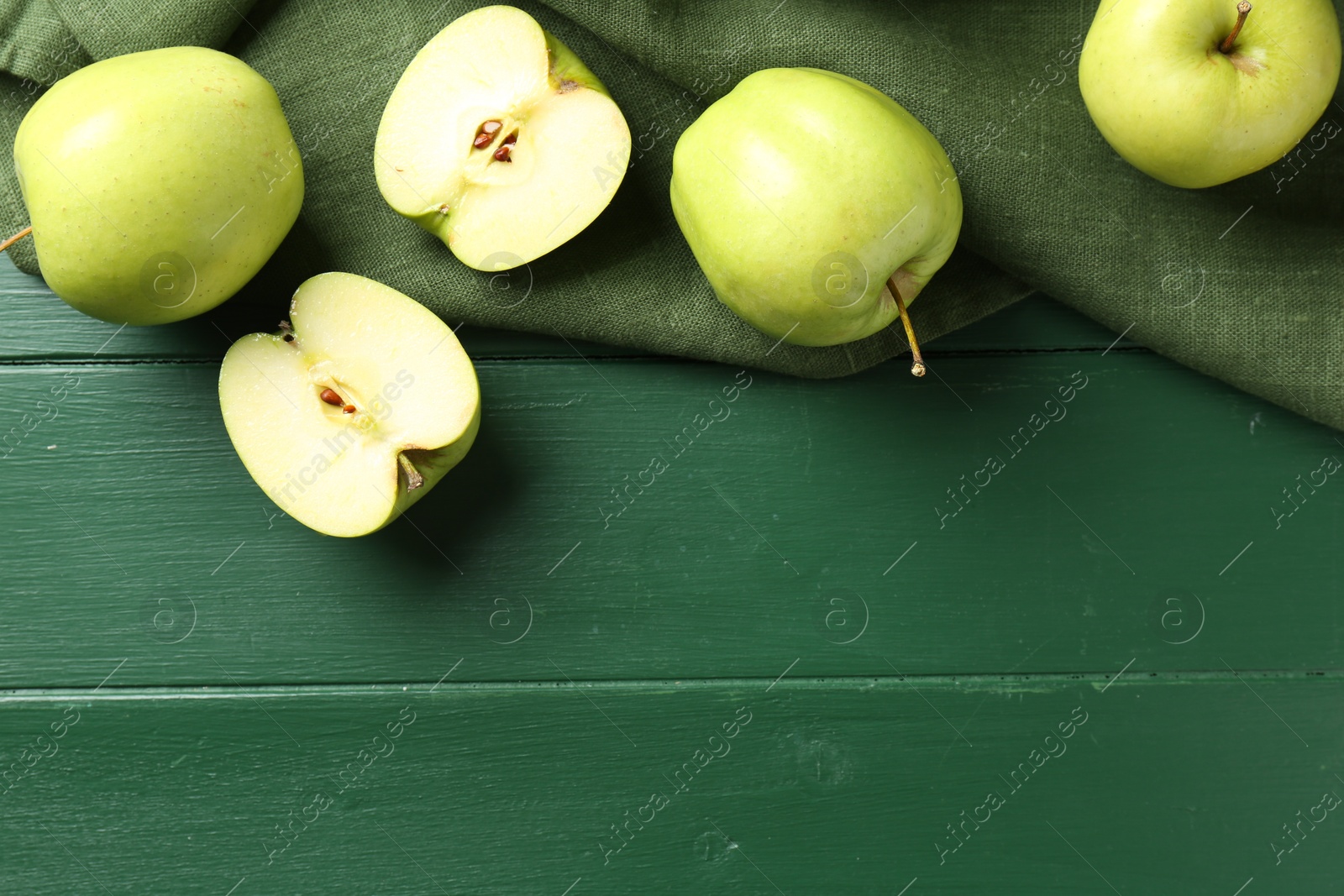 Photo of Ripe apples on green wooden table, top view. Space for text