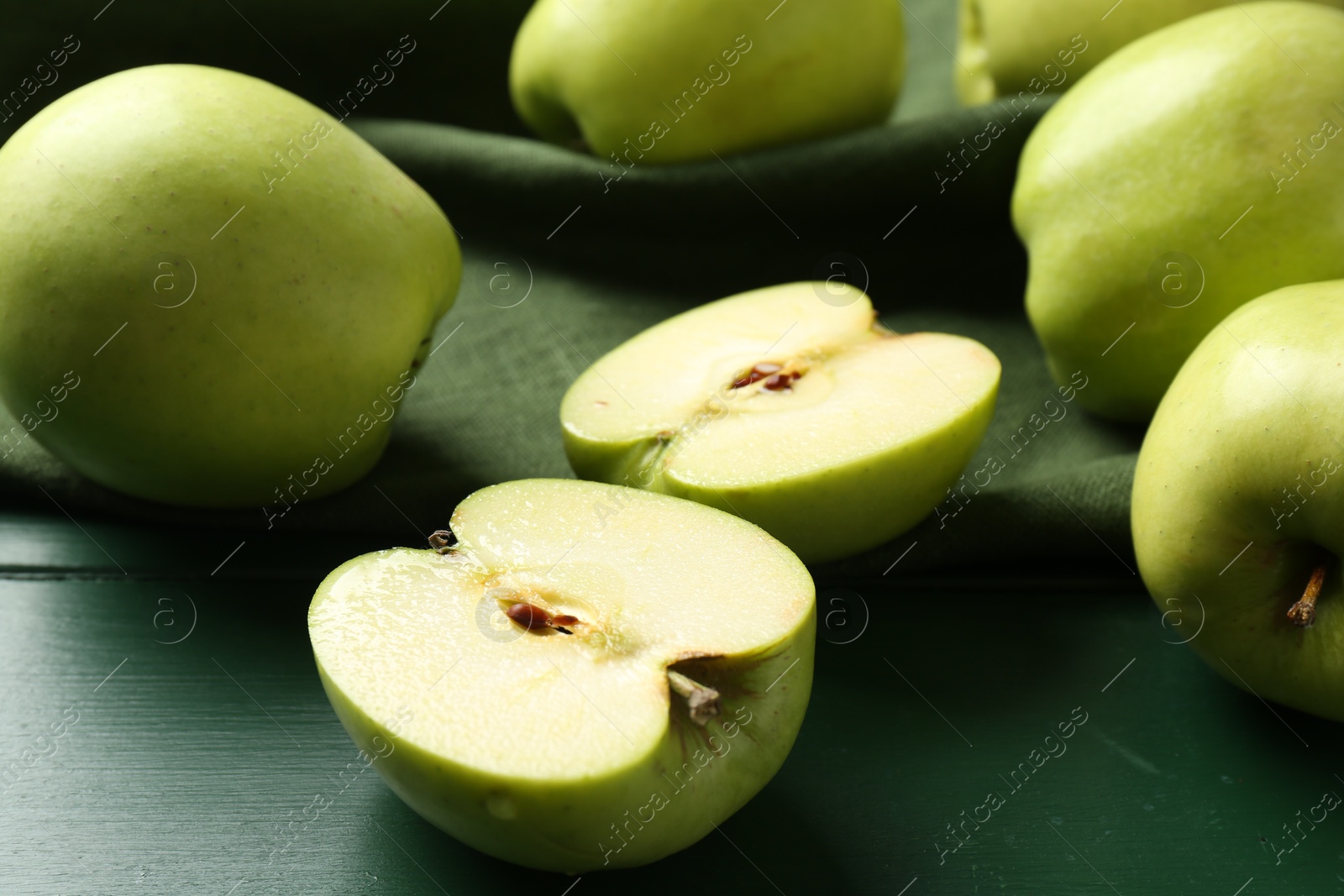 Photo of Ripe apples on green wooden table, closeup