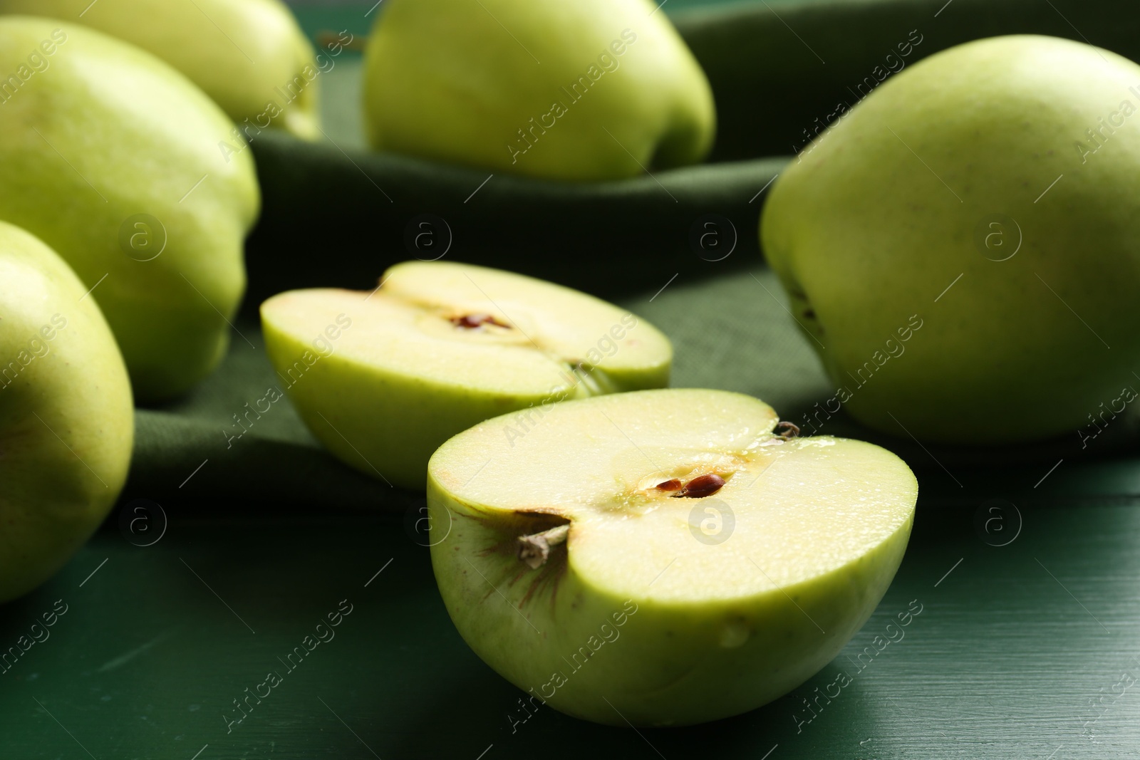 Photo of Ripe apples on green wooden table, closeup