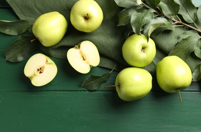 Photo of Ripe apples and leaves on green wooden table, top view