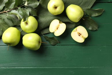 Photo of Ripe apples and leaves on green wooden table, top view