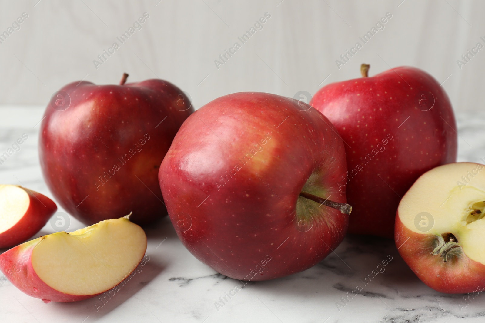 Photo of Ripe red apples on white marble table, closeup