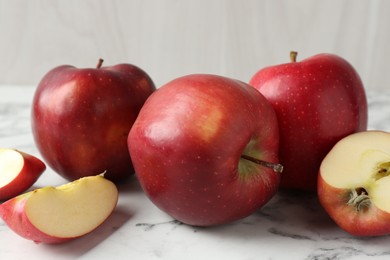 Photo of Ripe red apples on white marble table, closeup