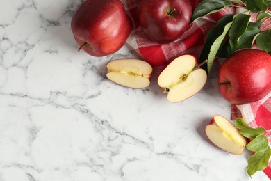 Photo of Ripe red apples and leaves on white marble table, top view. Space for text