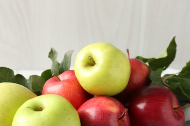 Photo of Ripe apples and green leaves on table, closeup