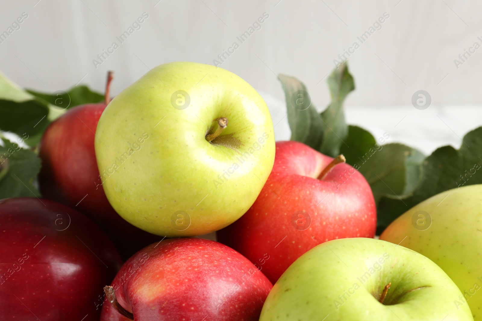 Photo of Ripe apples and green leaves on table, closeup