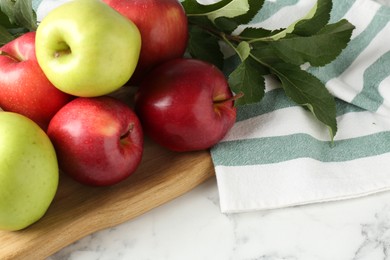 Photo of Ripe apples and green leaves on white marble table, closeup