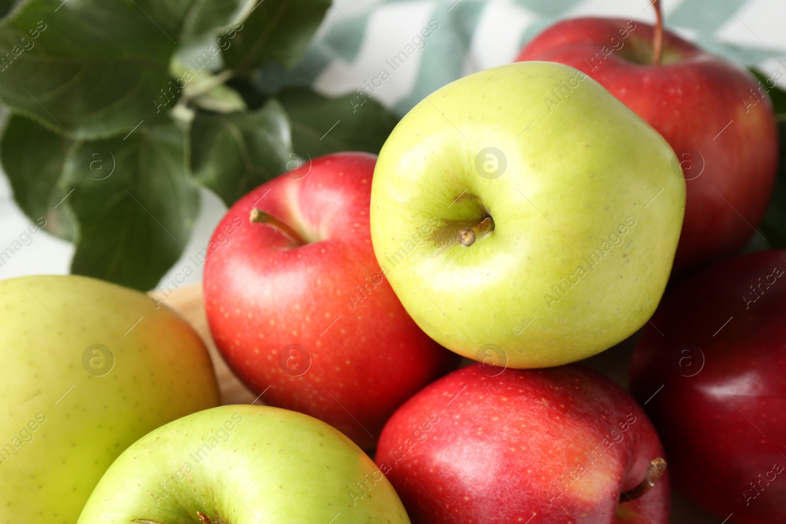 Ripe apples and green leaves on table, closeup Photo of Ripe apples and green leaves on table, closeup