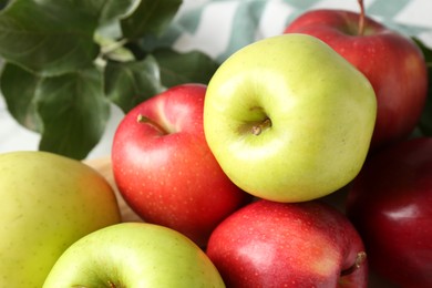 Photo of Ripe apples and green leaves on table, closeup