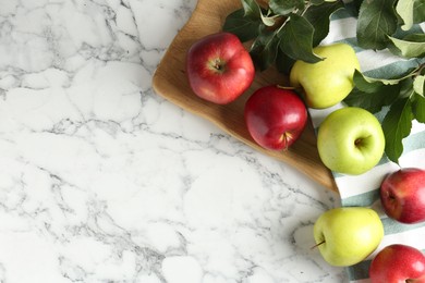 Photo of Ripe apples and green leaves on white marble table, top view. Space for text