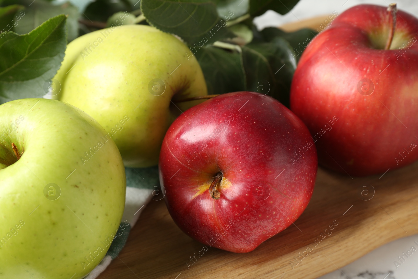 Photo of Ripe apples and green leaves on table, closeup