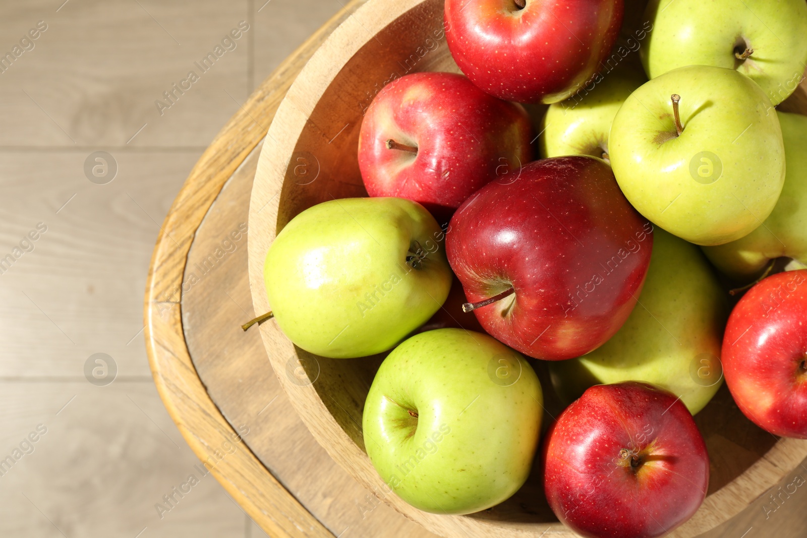 Photo of Ripe red and green apples in bowl on wooden chair, top view