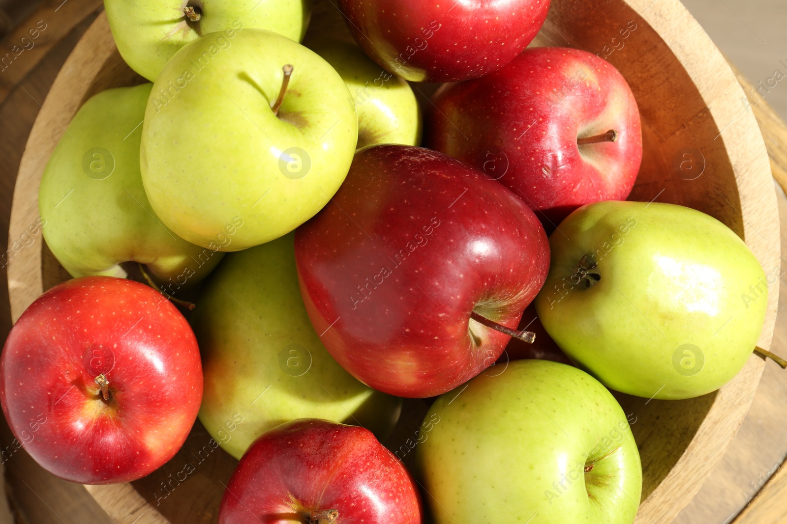 Photo of Ripe red and green apples in bowl on table, top view