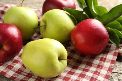 Photo of Ripe apples and green leaves on table, closeup