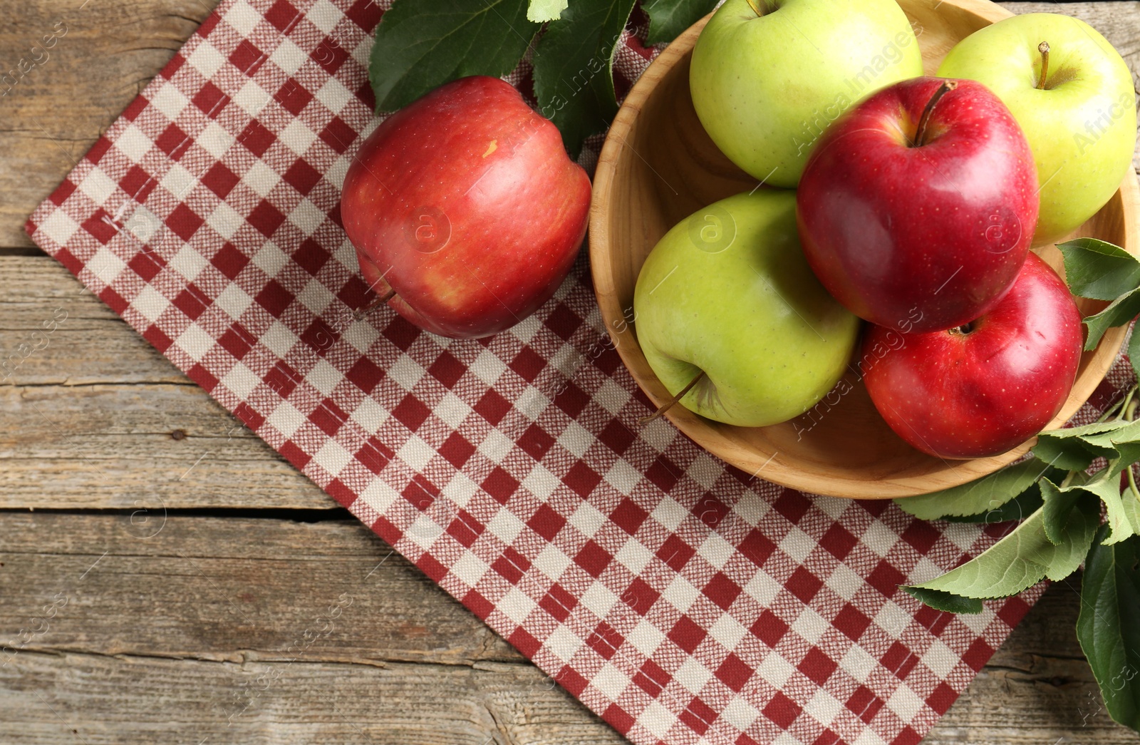 Photo of Ripe apples and green leaves on wooden table, top view