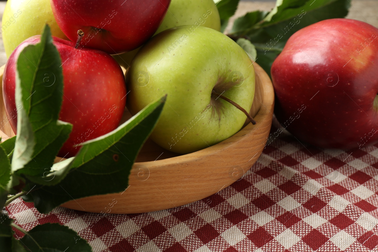 Photo of Ripe apples and green leaves on table, closeup