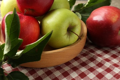 Photo of Ripe apples and green leaves on table, closeup