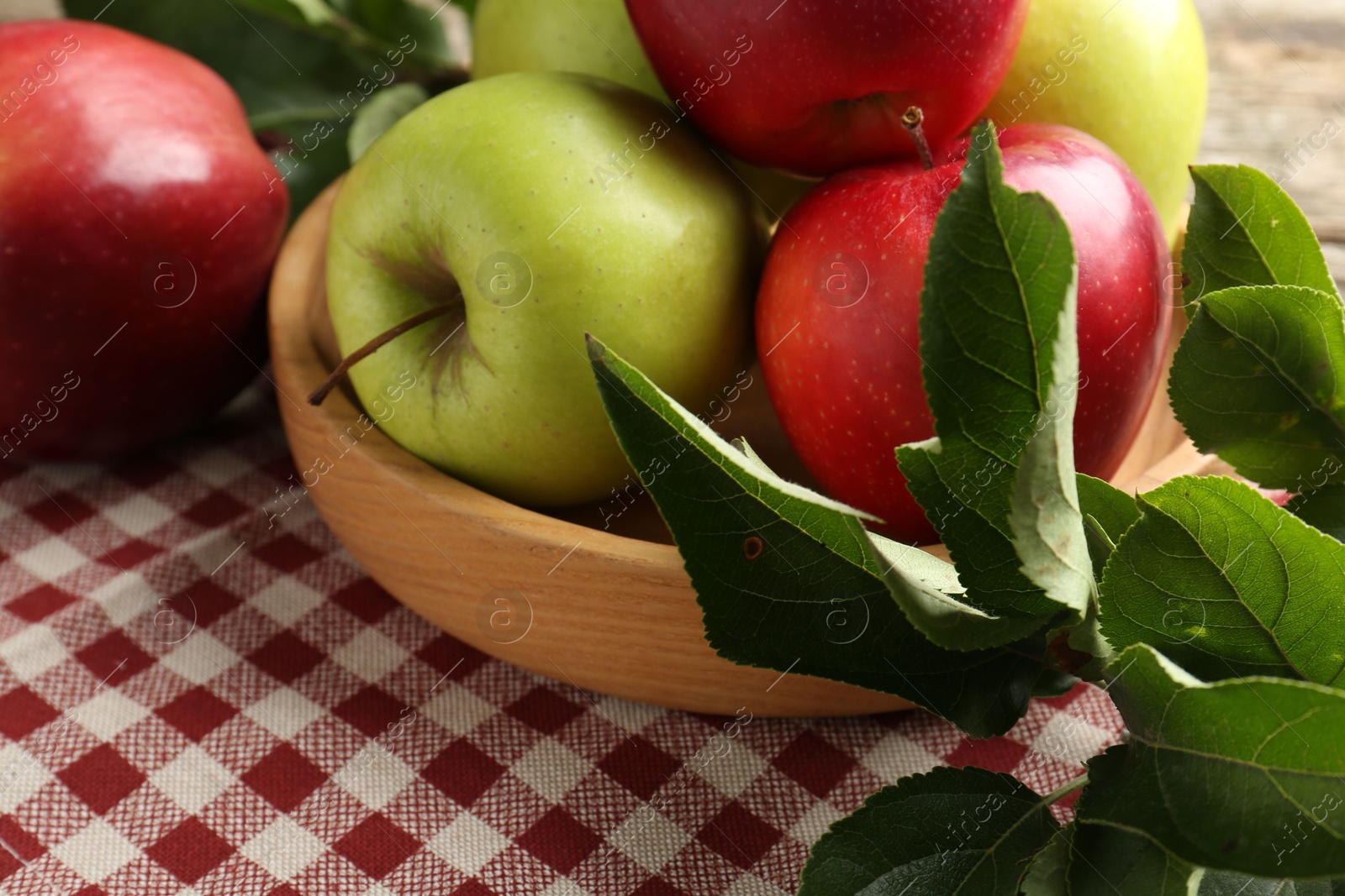 Photo of Ripe apples and green leaves on table, closeup