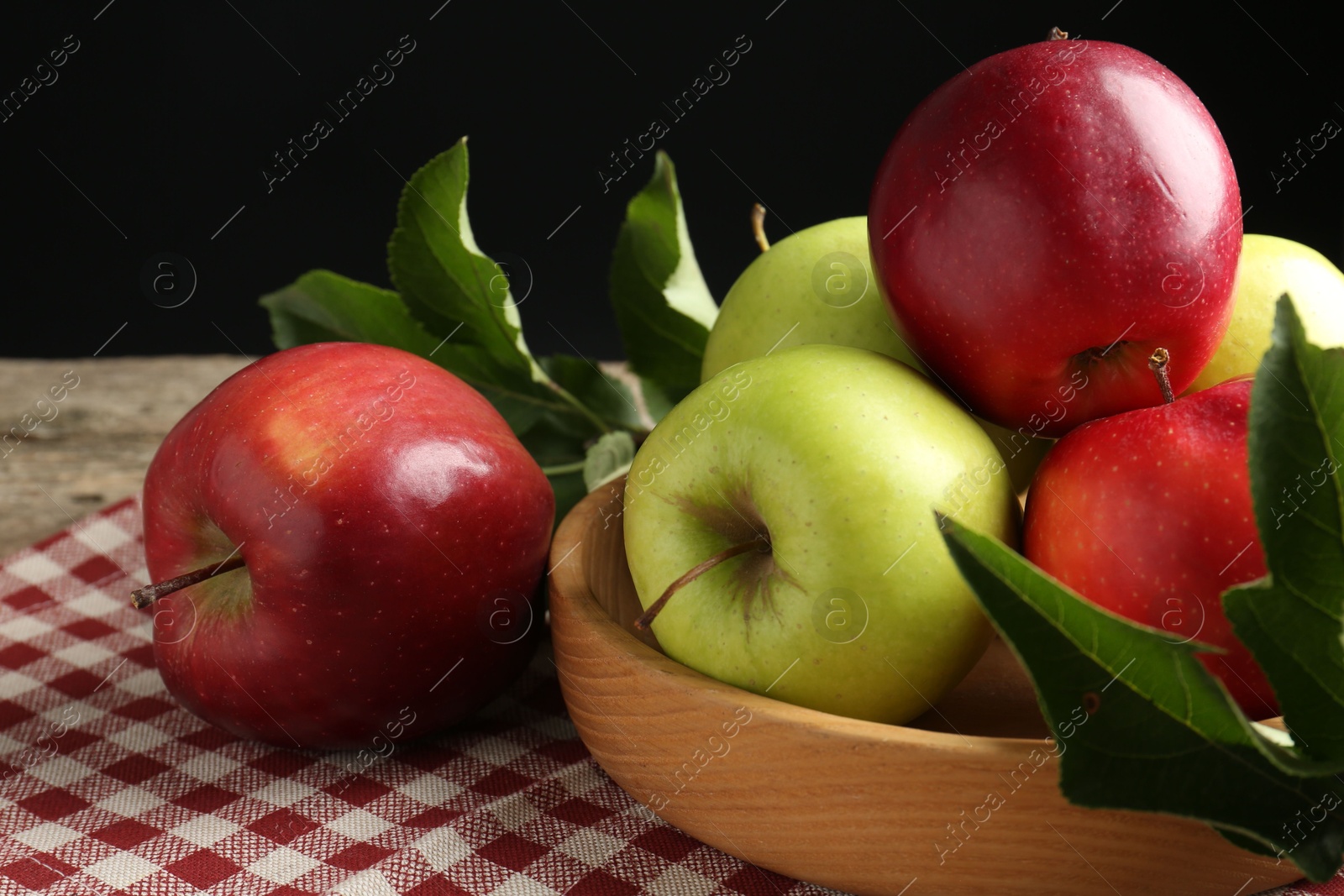 Photo of Ripe apples and green leaves on table, closeup