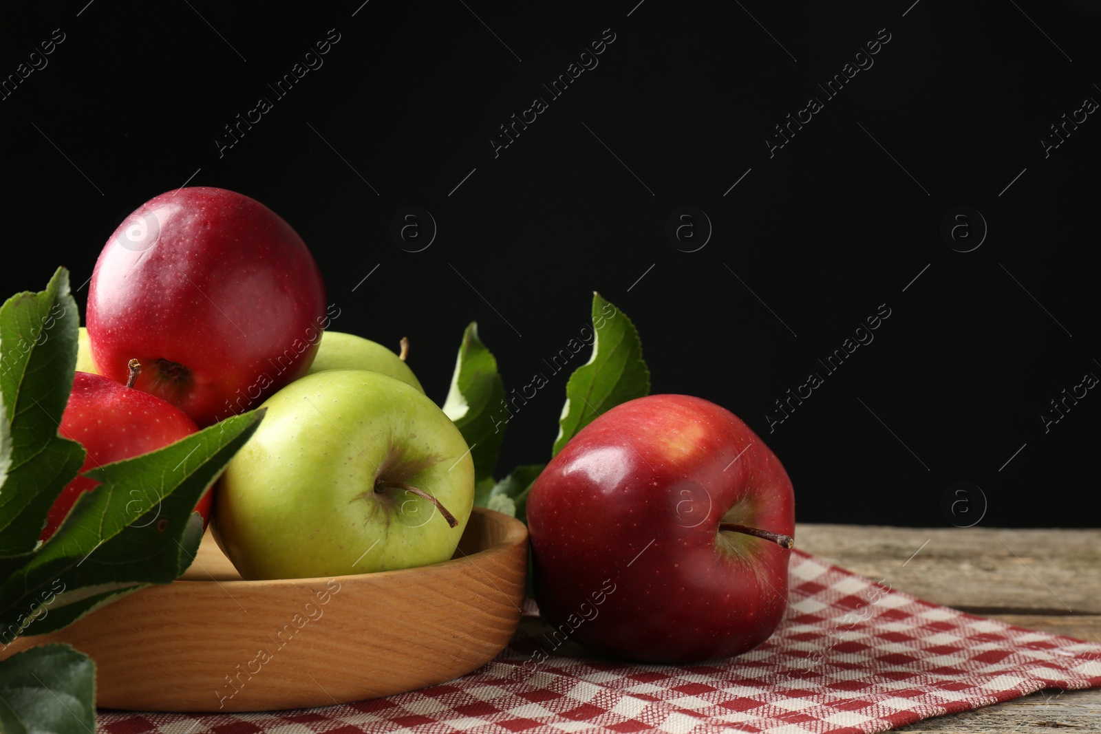 Photo of Ripe apples and green leaves on wooden table. Space for text