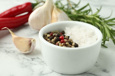 Photo of Sea salt, peppercorns, rosemary, chili peppers and garlic on white marble table, closeup