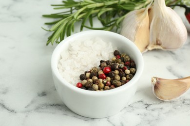 Sea salt, peppercorns, rosemary and garlic on white marble table, closeup