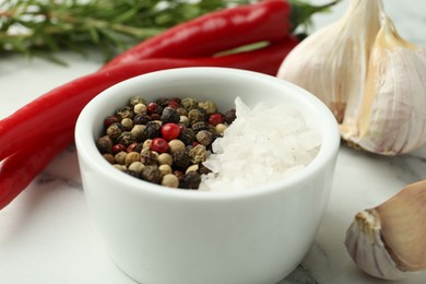 Photo of Sea salt, peppercorns, chili peppers and garlic on white marble table, closeup