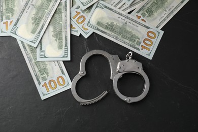 Photo of Corruption. Handcuffs and dollar banknotes on grey textured table, flat lay