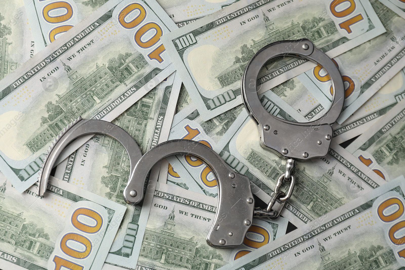 Photo of Corruption. Handcuffs on dollar banknotes, flat lay