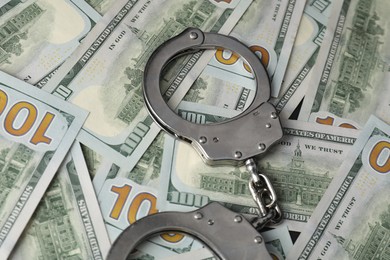 Photo of Corruption concept. Handcuffs on dollar banknotes, closeup