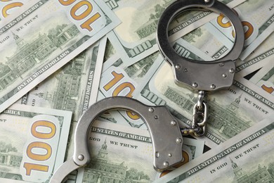 Photo of Corruption concept. Handcuffs on dollar banknotes, closeup