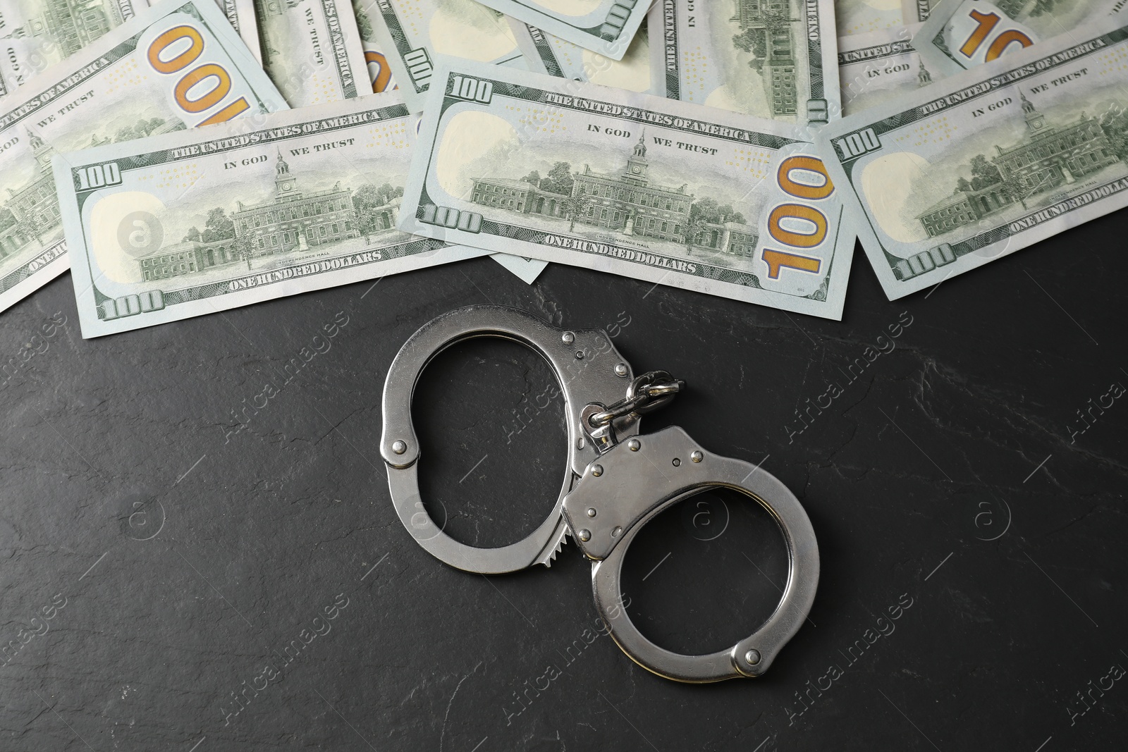 Photo of Corruption. Handcuffs and dollar banknotes on grey textured table, flat lay