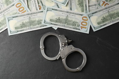 Corruption. Handcuffs and dollar banknotes on grey textured table, flat lay