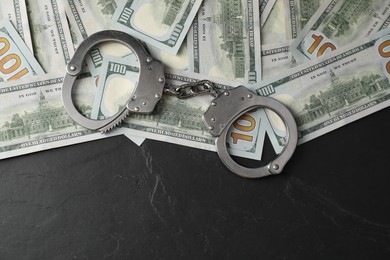 Photo of Corruption. Handcuffs and dollar banknotes on grey textured table, flat lay