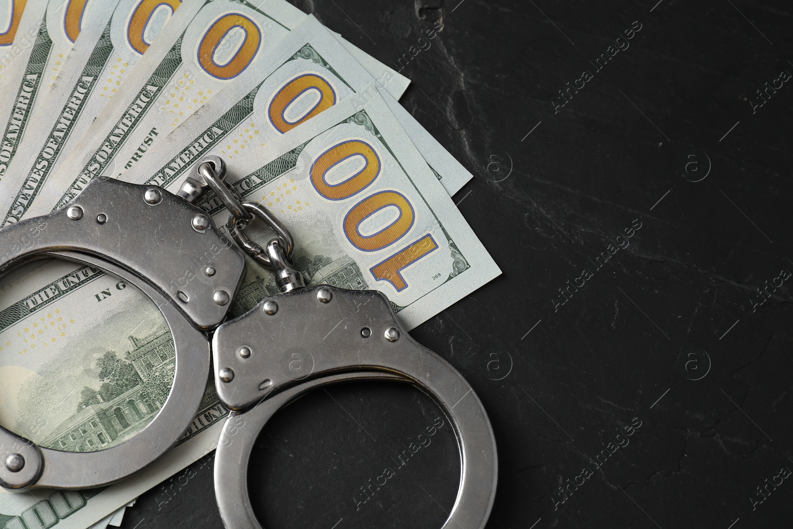 Photo of Corruption. Handcuffs and dollar banknotes on grey textured table. Space for text