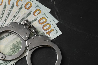 Photo of Corruption. Handcuffs and dollar banknotes on grey textured table. Space for text