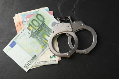 Photo of Corruption. Handcuffs and euro banknotes on grey textured table, flat lay