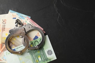 Photo of Corruption. Handcuffs and euro banknotes on grey textured table, flat lay. Space for text